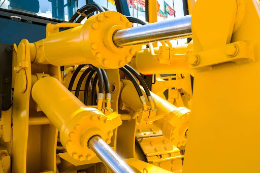 A yellow machine undergoing hydraulic cylinder repairs