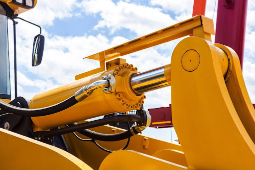 A yellow machine undergoing hydraulic cylinder repairs